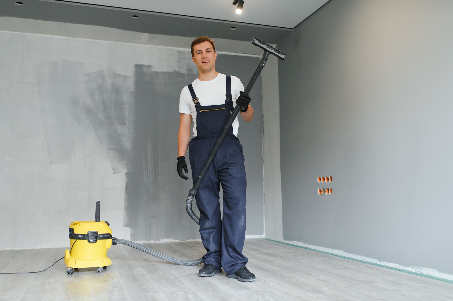 A worker vacuums a room after repairing the floors. Apartment after renovation with a vacuum cleaner.